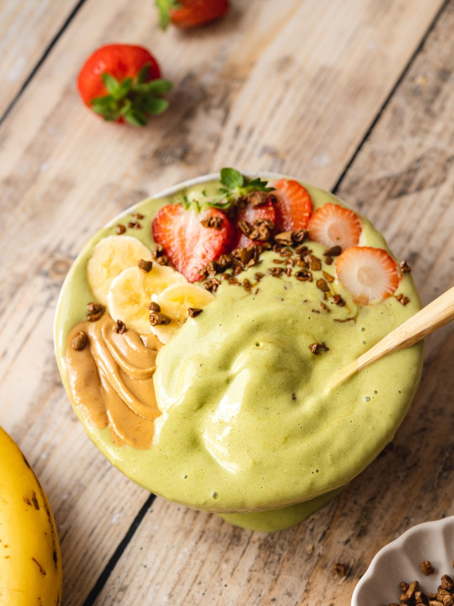 Green smoothie bowl with fruit on a wooden table